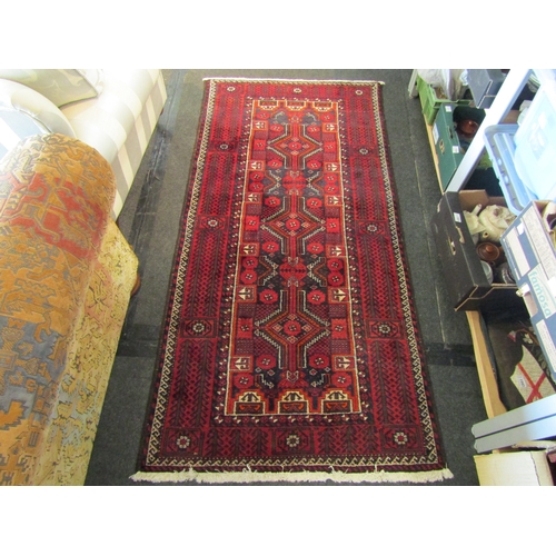 1467 - A Persian red and beige ground geometric design wool rug with tasselled ends, 200cm x 100cm