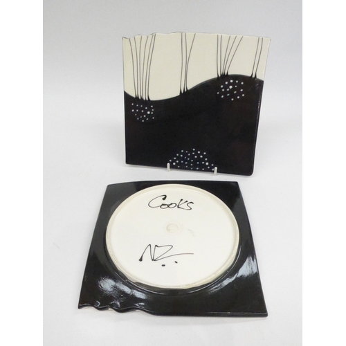 7033 - Two black and white slipware decorated square plates, marked 'Cooks NZ' to base. 20.5cm x 21cm   