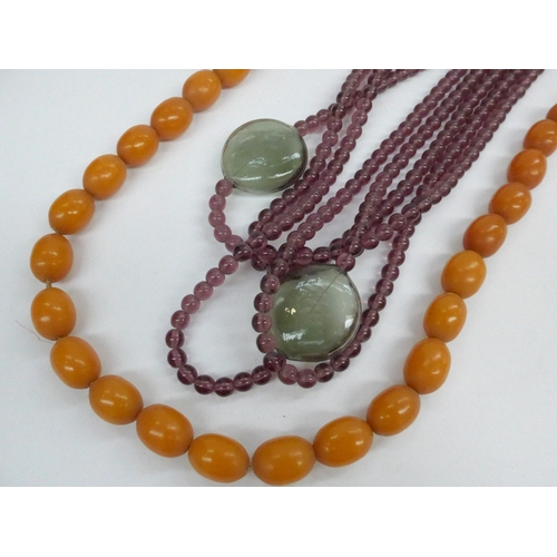 7352 - An amethyst coloured four strand bead necklace with two bubble glass beads in grey