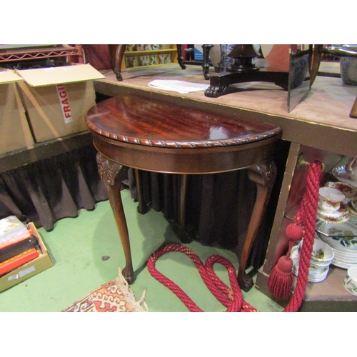 4003 - A Georgian mahogany demi-lune games table, the hinged fold-over top on carved cabriole legs with hai... 