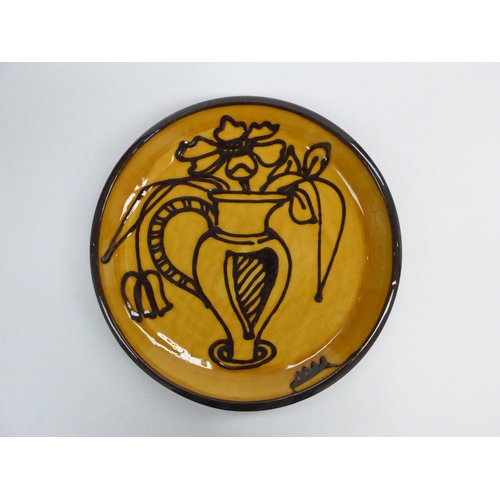 7132 - MARY WONDRAUSCH (1923-2016) large red eartheware plate with dark brown slip trailed image of a jug a... 