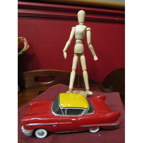 4125 - A painted terracotta car, together with an artist's articulated wooden figure