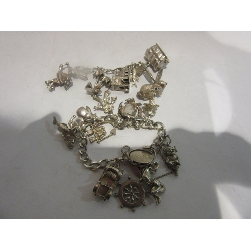 4395 - A charm bracelet with white metal and silver charms with further charms on a separate chain includin... 