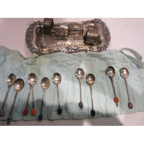 4418 - A roll of miscellaneous EPNS coffee bean spoons, a pair of plated candle snuffers and two napkin rin... 