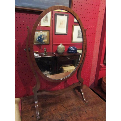 4081 - An oval dressing table mirror set on a footed frame, 61cm tall