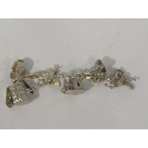 4395 - A charm bracelet with white metal and silver charms with further charms on a separate chain includin... 