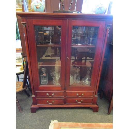 1105 - A mahogany glazed front bookcase with four drawers flanked by columns on bracket feet, 128cm tall x ... 