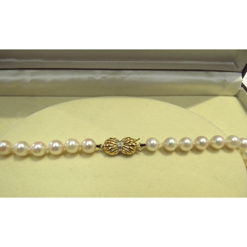 9373 - A single strand pearl necklace, 6mm diameter with a diamond set 9ct gold bow clasp, 28cm long, in Di... 