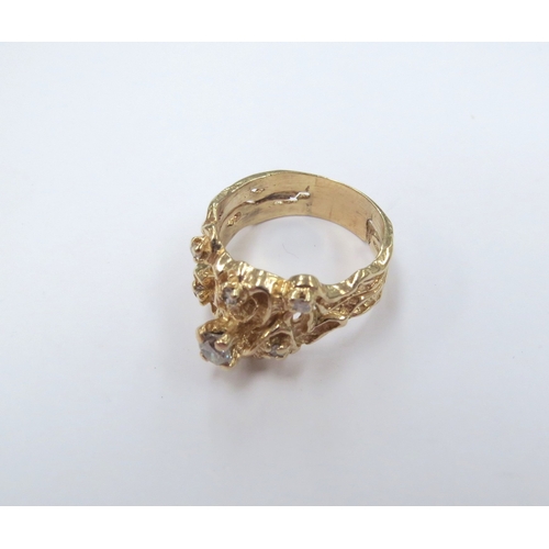 9024 - An unmarked gold ring of naturalistic form set with six diamonds, the larger in claw mount. Size N, ... 