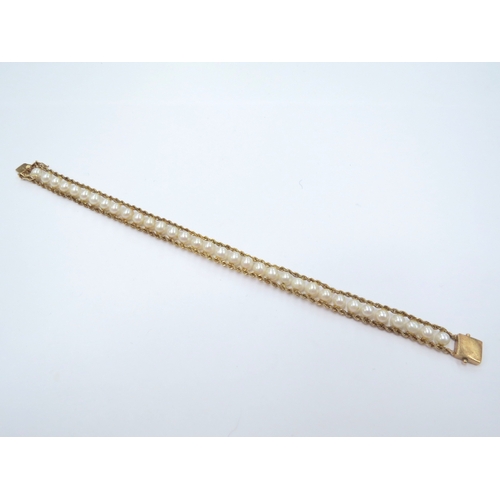 9066 - A gold pearl bracelet, the two twisted bands of gold with a row of pearls in between, stamped 14k, 1... 