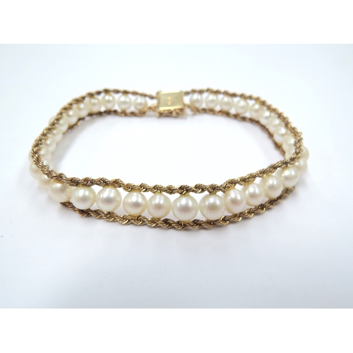 9066 - A gold pearl bracelet, the two twisted bands of gold with a row of pearls in between, stamped 14k, 1... 