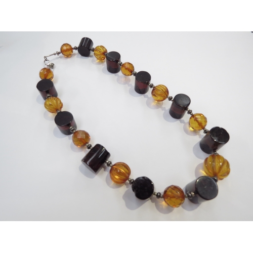 9307 - An amber bead necklace, dark barrel beads, melon fluted and facet cut examples, 46cm long