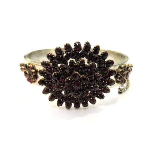 9367 - An Austro-Hungarian stiff hinged bangle with clusters of red coloured stones