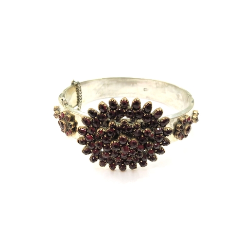 9367 - An Austro-Hungarian stiff hinged bangle with clusters of red coloured stones