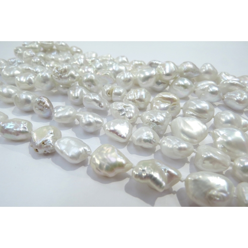 9289 - An opera length irregular shaped freshwater pearl necklace, clasp stamped 14k, 180cm long