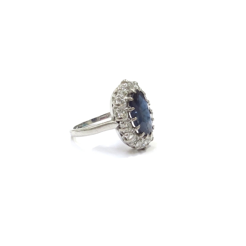 9150 - A platinum sapphire and diamond cluster ring the central oval sapphire 11mm x 7mm framed by fourteen... 