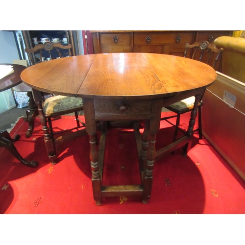 1076 - A country oak gateleg dining table, turned supports joined by a stretcher, 78cm tall x 117cm long x ... 