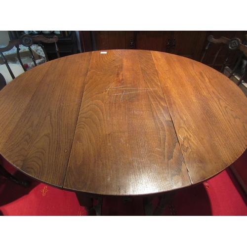 1076 - A country oak gateleg dining table, turned supports joined by a stretcher, 78cm tall x 117cm long x ... 