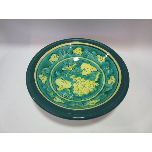 1556 - A large shallow pottery bowl decorated in green and yellow fruiting vines, 36cm diameter