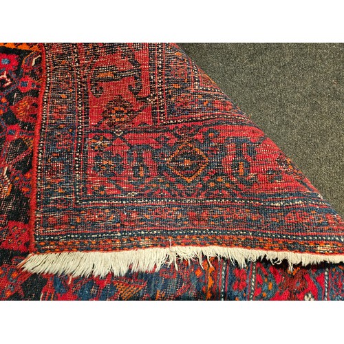 1025A - An Eastern red and blue ground geometric design rug with multiple borders, worn, 270cm x 140cm