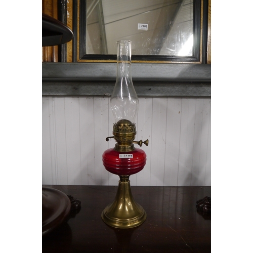 2104 - A brass and red glass oil lamp