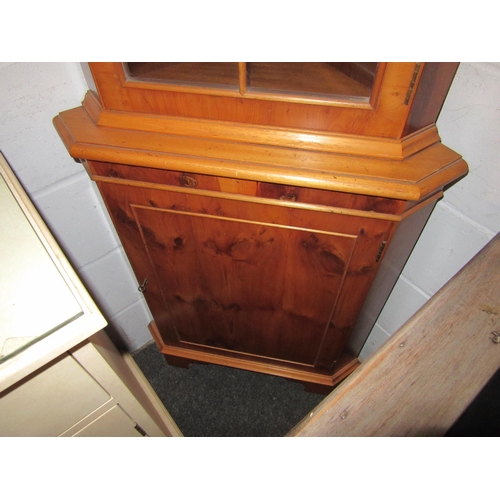 1012 - A yew wood veneer, glazed corner cabinet, shelved interior over shelved cupboard, with key.  46cm x ... 