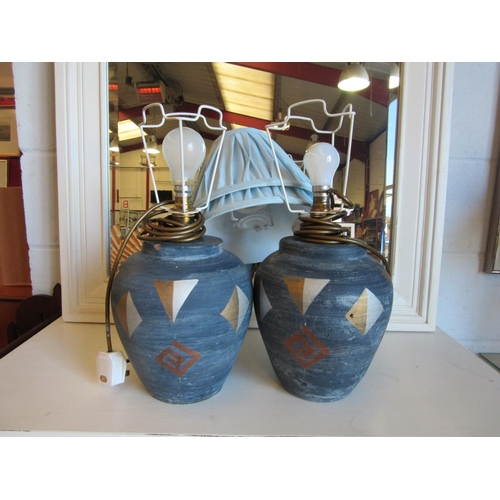 1020 - A pair of painted table lamp bases, in blue and gilt design, with pale blue pleated shades