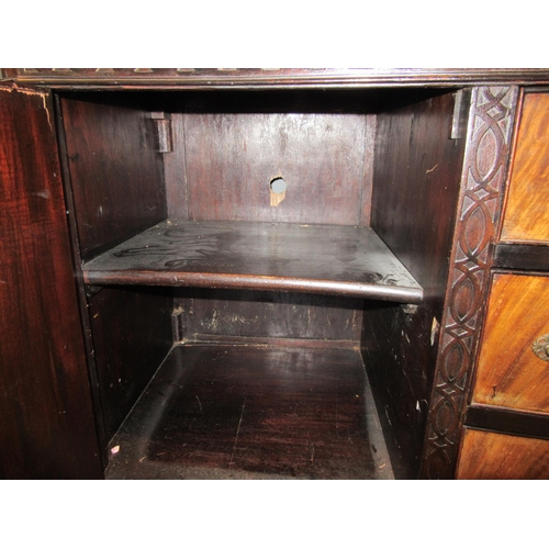 1073 - An oak sideboard, three central drawers flanked by shelved cupboards, blind fret carved with ball an... 