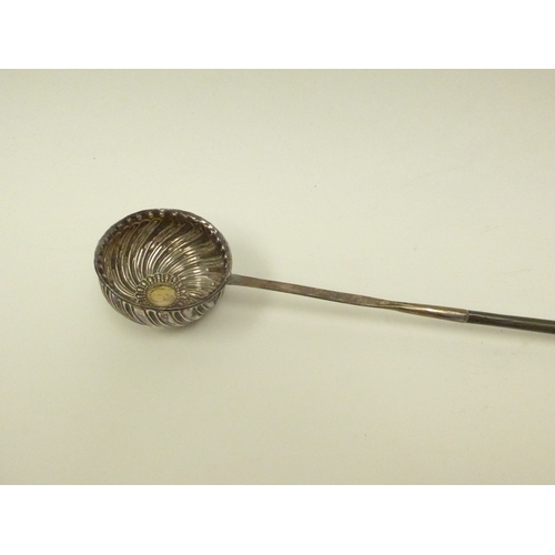 7115 - A Georgian white metal toddy ladle of wrythen form with long whale bone handle.  The bowl inset with... 