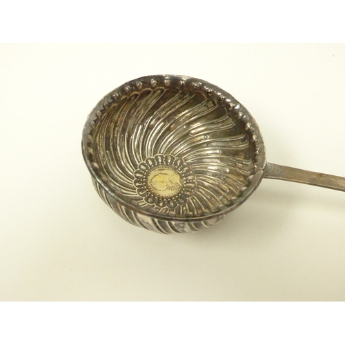 7115 - A Georgian white metal toddy ladle of wrythen form with long whale bone handle.  The bowl inset with... 