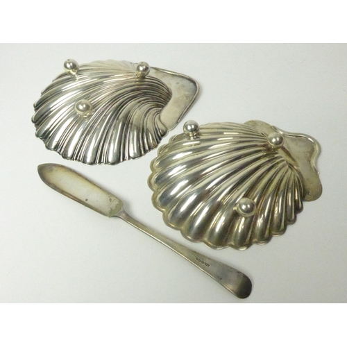 7130 - Two silver shell form butter dishes and knife including Dublin West & Son 1906 and London 1902, 178g