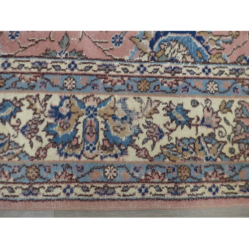 7631 - A pink ground carpet with substantial wear to one side, 247cm x 352cm