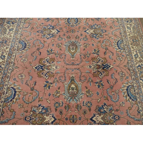 7631 - A pink ground carpet with substantial wear to one side, 247cm x 352cm