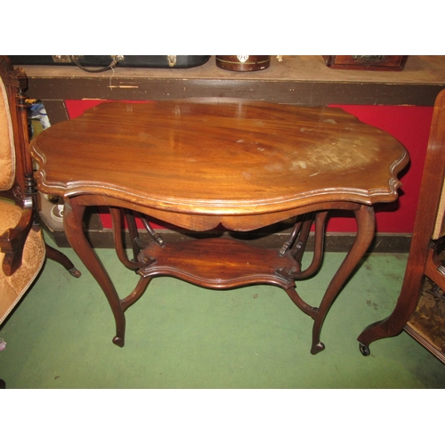 4018 - An Art Nouveau walnut two tier lamp table in the manner of 'Liberty & Co' the shaped top over unusua... 