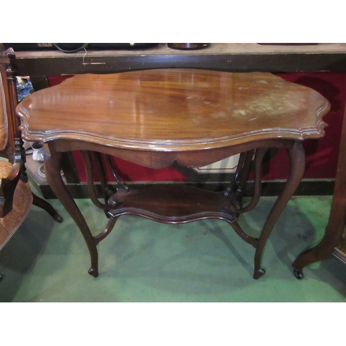 4018 - An Art Nouveau walnut two tier lamp table in the manner of 'Liberty & Co' the shaped top over unusua... 