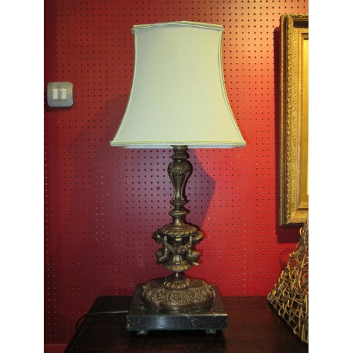 4029 - A brass bronze effect figural table lamp with fern and mask detail on marble base, with pale green s... 