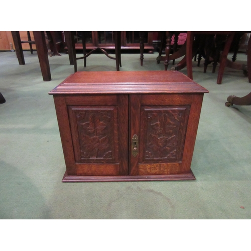 4076 - An early 20th Century oak tobacco cabinet with ivy leaf carved detail, associated ceramics and drawe... 