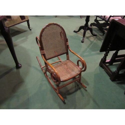 4217 - A child's bentwood rocking chair, the cane seat and back rest with ornate brass stud decoration