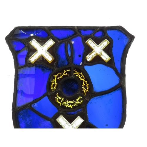 7626 - A shield shaped leaded glass panel, cobalt blue, central roundel with X's top and bottom, some damag... 