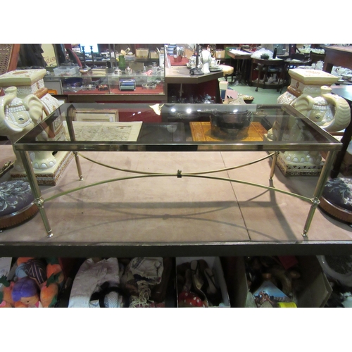 4309 - A brass and smoky glass rectangular occasional table on tapering legs united by an 'X' framed stretc... 