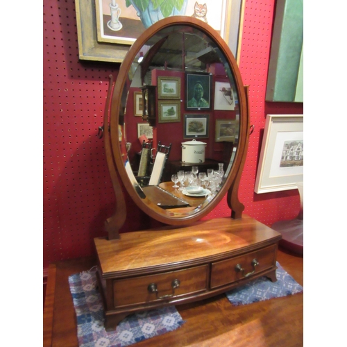 4110 - A George III revival mahogany toilet mirror, the tilting bevel edged oval mirror on a bow front base... 