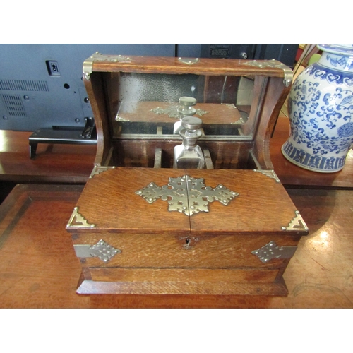 1128 - A Victorian oak three bottle tantalus with opening section to front, single drawer, metal mounts (no... 