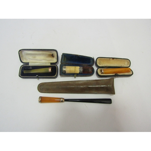 1351 - An Edwardian amber cheroot holder with 9ct gold mounts, another amber cheroot holder, mount unmarked... 