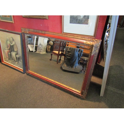 1064 - A rectangular bevel edged red and gilt framed wall mirror, 75cm x 106cm