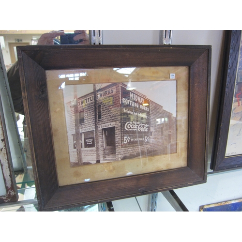 7304 - A framed and glazed black and white photograph depicting an old shop advertising Coca-Cola