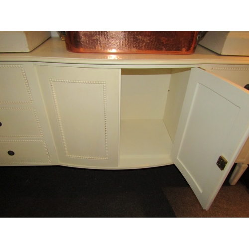 1023 - A Laura Ashley white painted sideboard of six drawers and central two door cupboard with key on squa... 