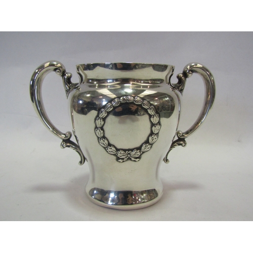 1304 - A white metal twin handled pot, ribbon and swag with vacant cartouche, marked sterling to base, dent... 