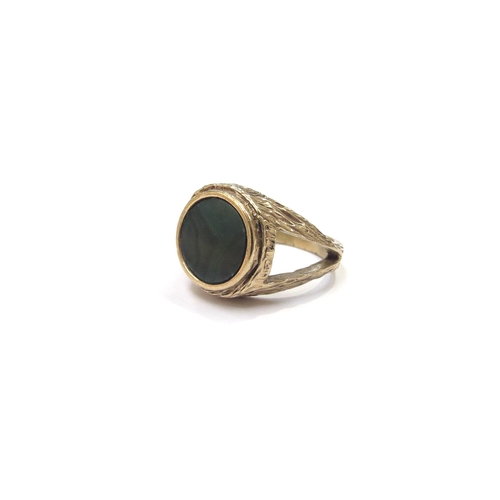 6190 - A 9ct gold ring set with circular malachite panel, textured open shoulders. Size I/J, 6.2g