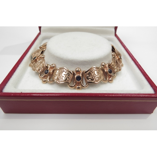 6177 - A 9ct rose gold bracelet with engraved panels separated with links set with single sapphires, 20cm l... 