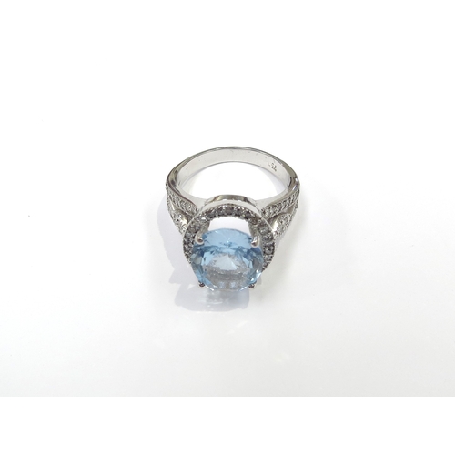 6135 - An 18ct white gold ring centrally set with a large oval topaz framed by diamonds with diamond set op... 